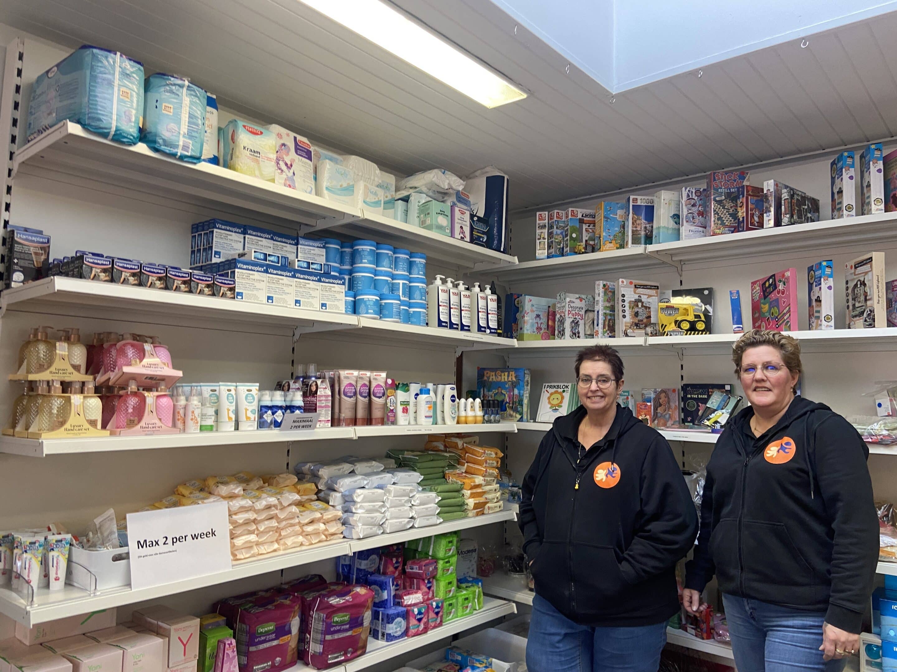Weggeefhoek Annemarie en Yvonne staan voor een schap met verzorgingsproducten in de Weggeefhoek.